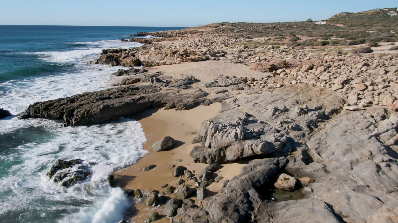 Rocky beach cove with surf, sand, and open ocean