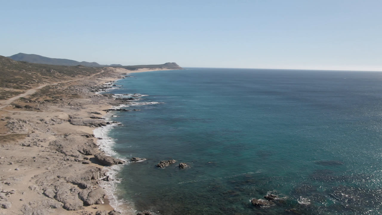 Wide aerial coastline with surf and distant headland