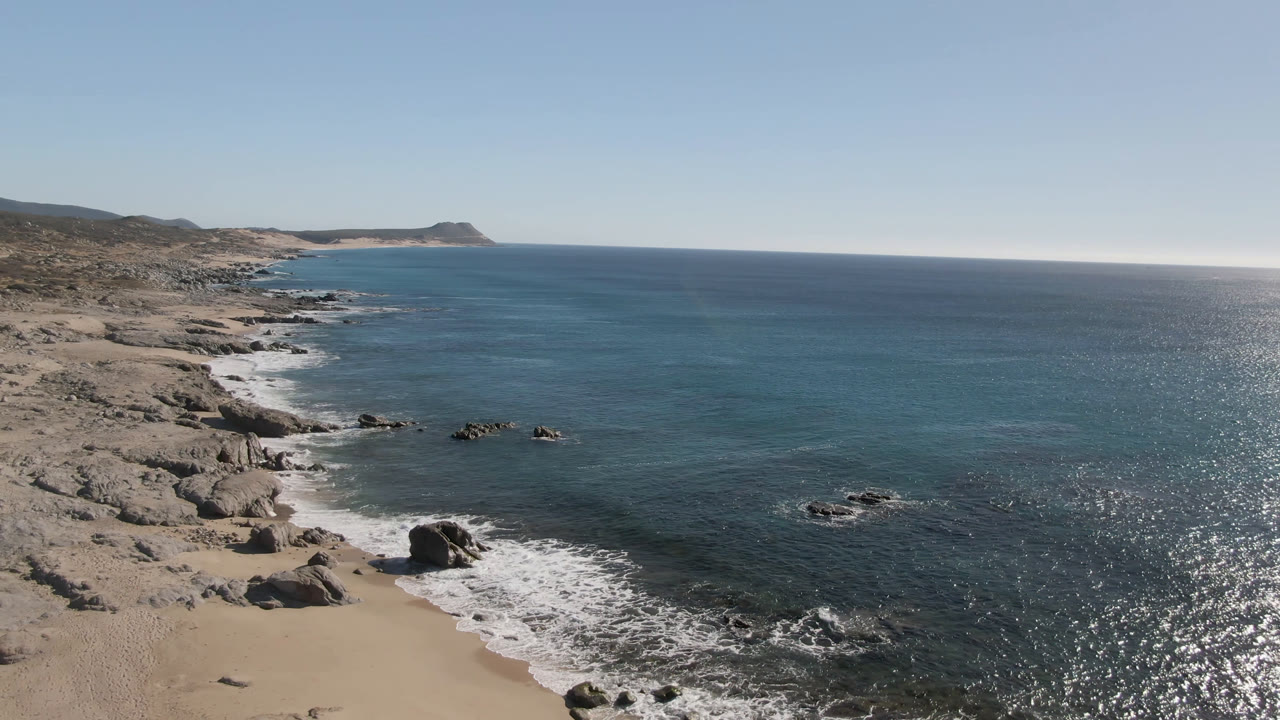 Elevated view of rocky beach, blue ocean, and clear sky