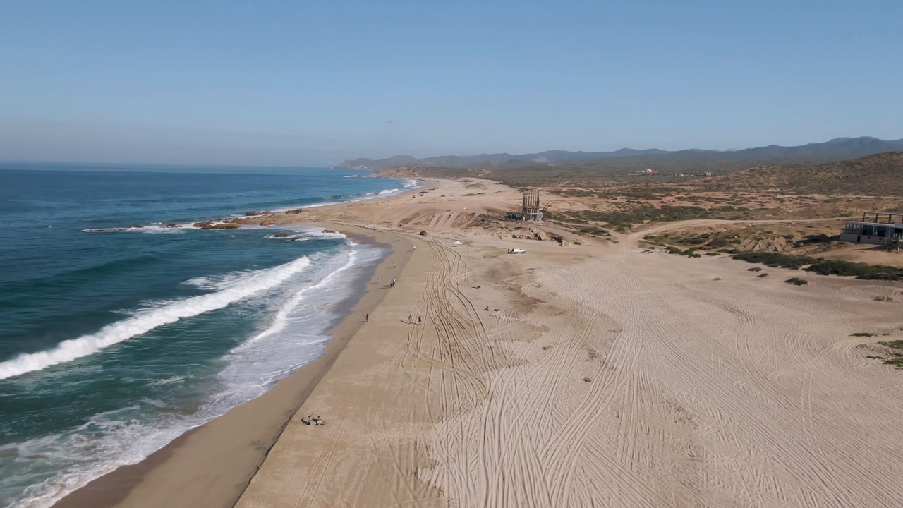 Aerial view of ocean waves beside a wide sandy beach.