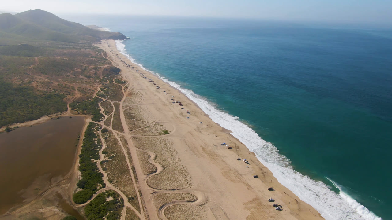 Wide aerial coastline with ocean on the right and sandy beach below