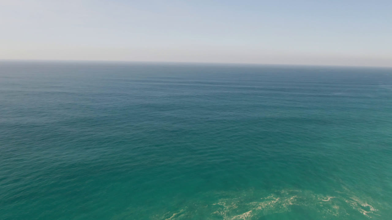 Ocean horizon with white surf patterns near the lower frame