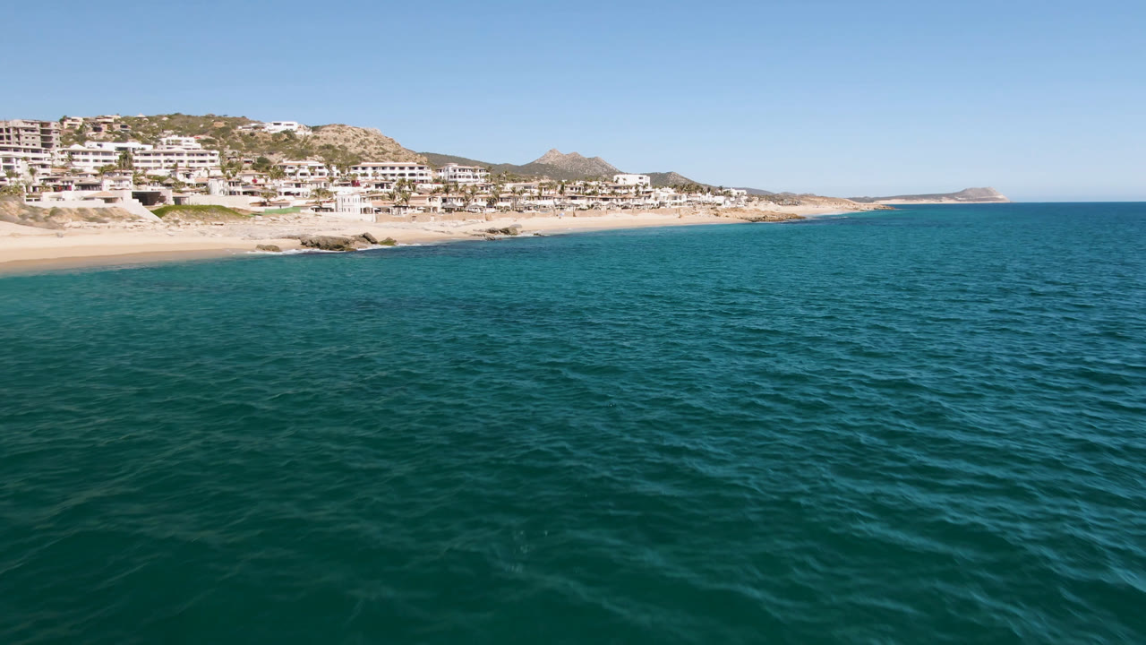 Wide ocean view with beach, hillside buildings, and blue sky