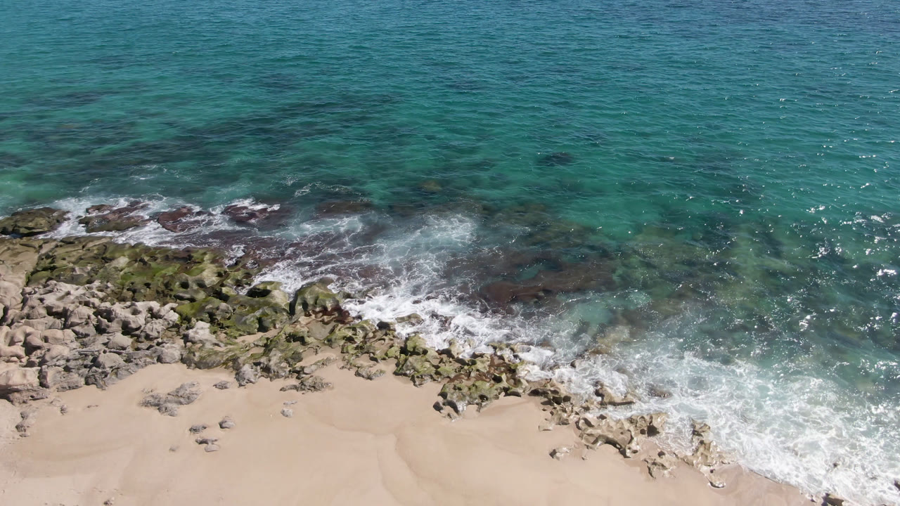 Clear ocean water above a rocky beach edge with surf.
