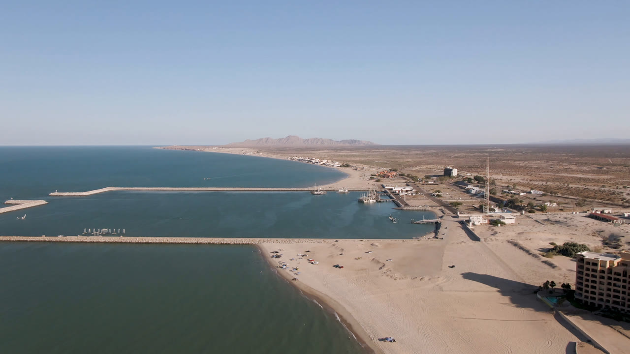 Aerial view of beach, ocean, pier, desert, and distant mountains.
