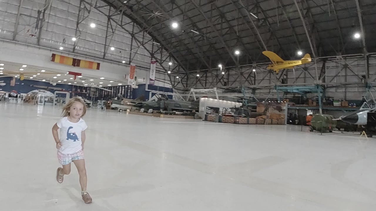 Girl running closer across the hangar floor.