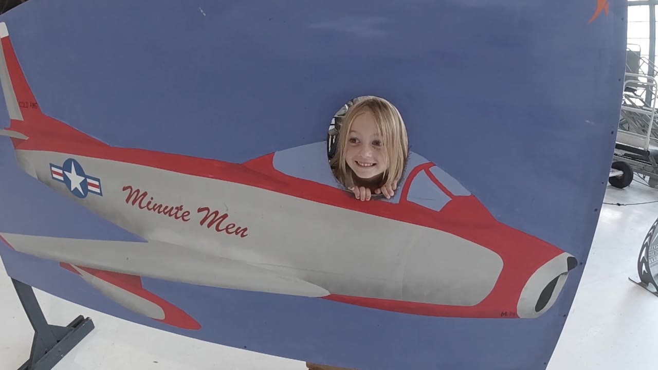 At 0:02, the woman looks toward the camera from the cockpit cutout, with the Minute Men script and star insignia still readable on the fuselage.
