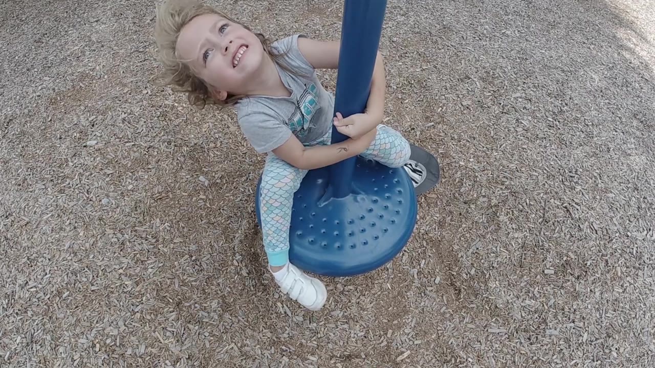 Toddler smiling up while holding the blue pole.