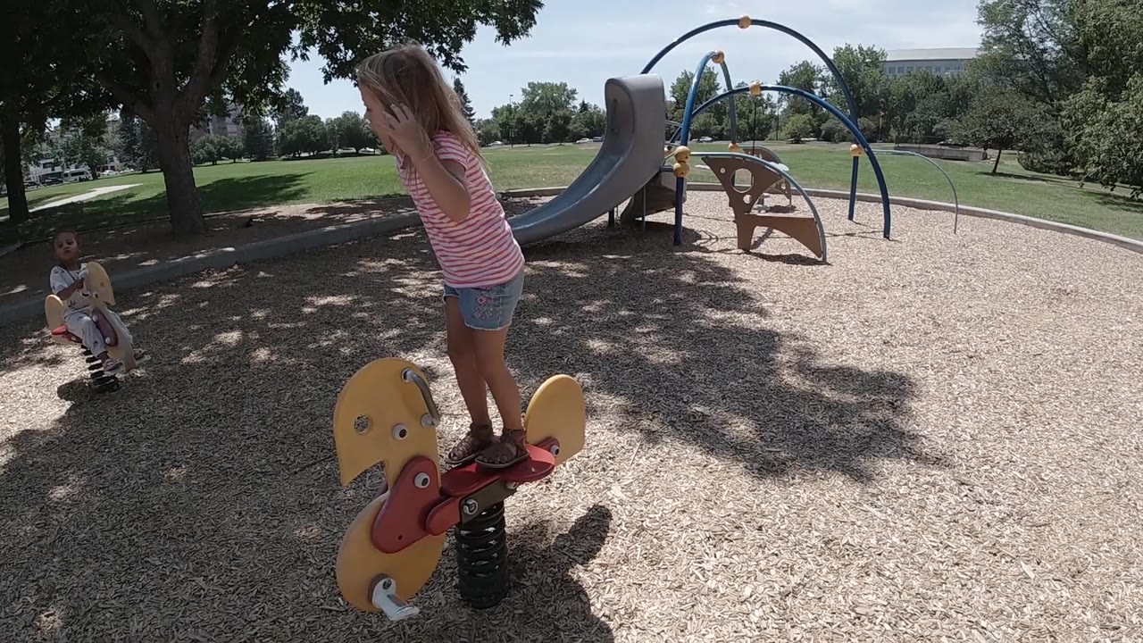 Toddler girl balances on the yellow spring rider.