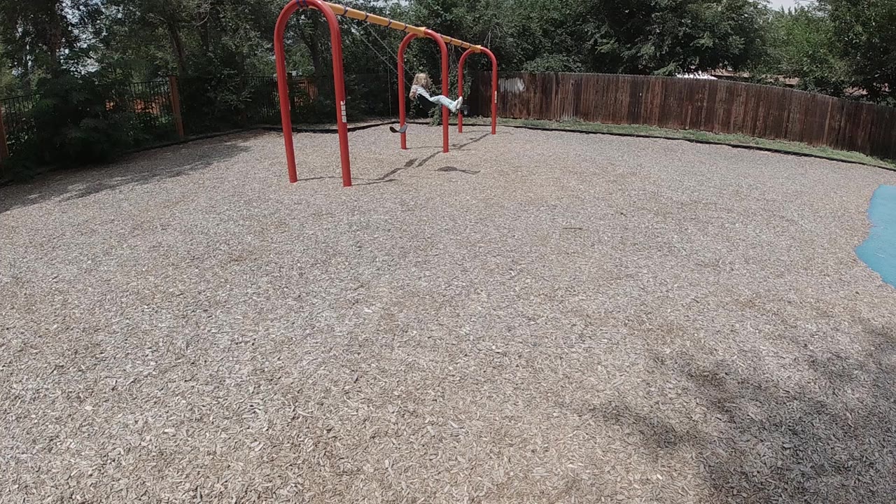 Child climbing across red playground bars.