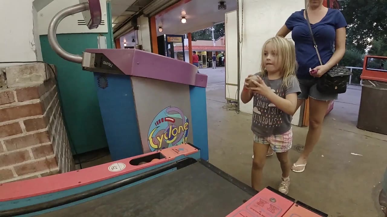Girl faces the arcade game while holding the ball near her chest.