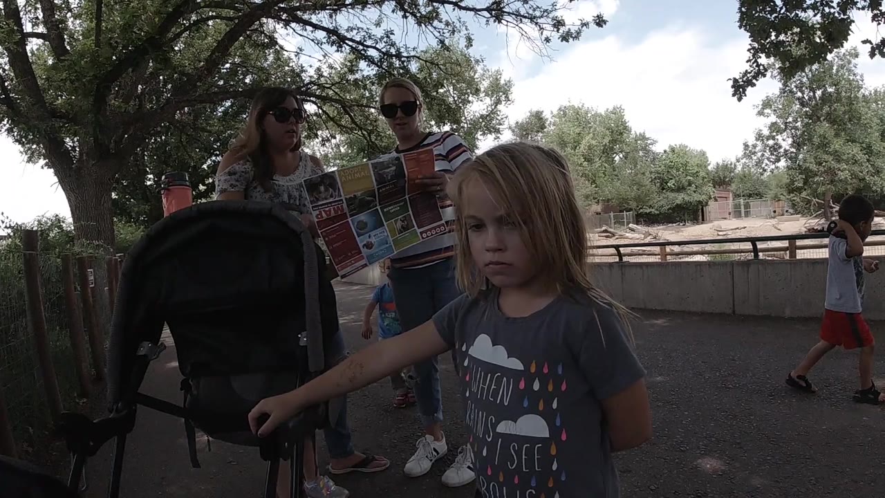 Girl holds stroller handle while adults read a map