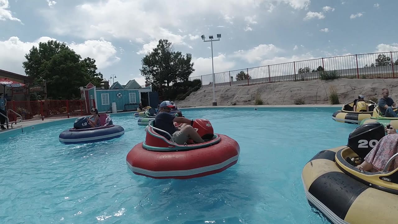 Red bumper boat near the camera with other boats in the pool.