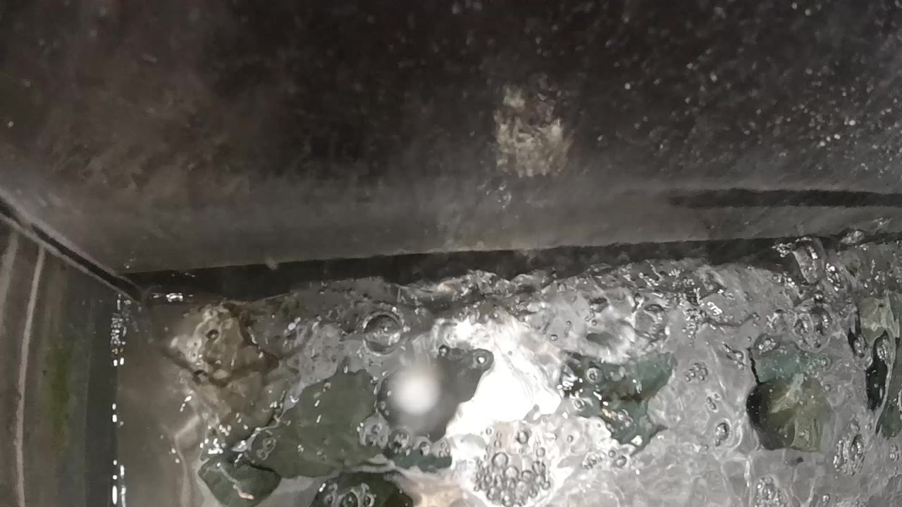 Overhead view of churning boiling water in a stainless steel pot with shifting white foam and dark bubble clusters; no people visible