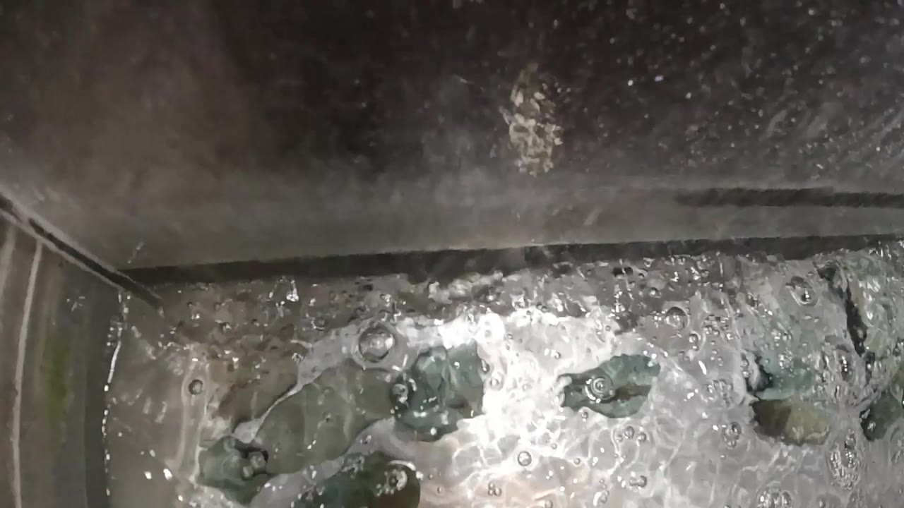 Overhead view of a rolling boil in a stainless steel pot showing white foam concentrated toward center and dark bubble formations near the pot walls; no people visible