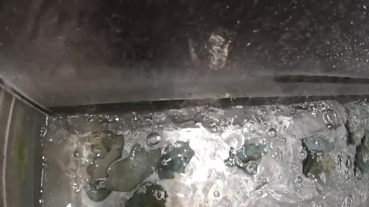 Overhead close-up of vigorously boiling water in a stainless steel pot with turbulent white foam and rising dark bubbles; no people visible