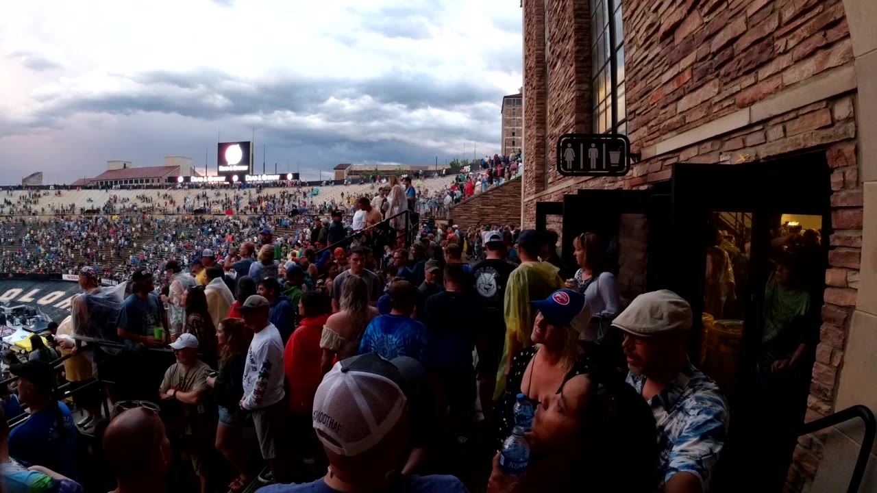 People standing and moving near a brick building entrance at a crowded event.