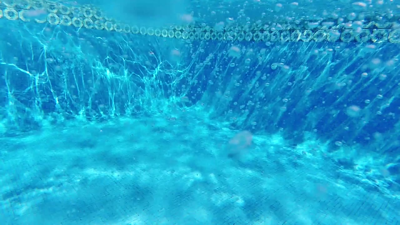 Underwater view with a curved bright arc of the water surface across the upper portion and caustic patterns below