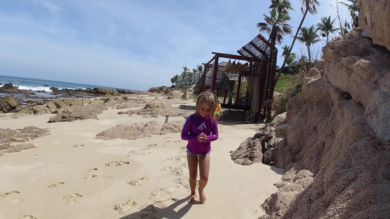 Girl approaching camera on bright sandy beach