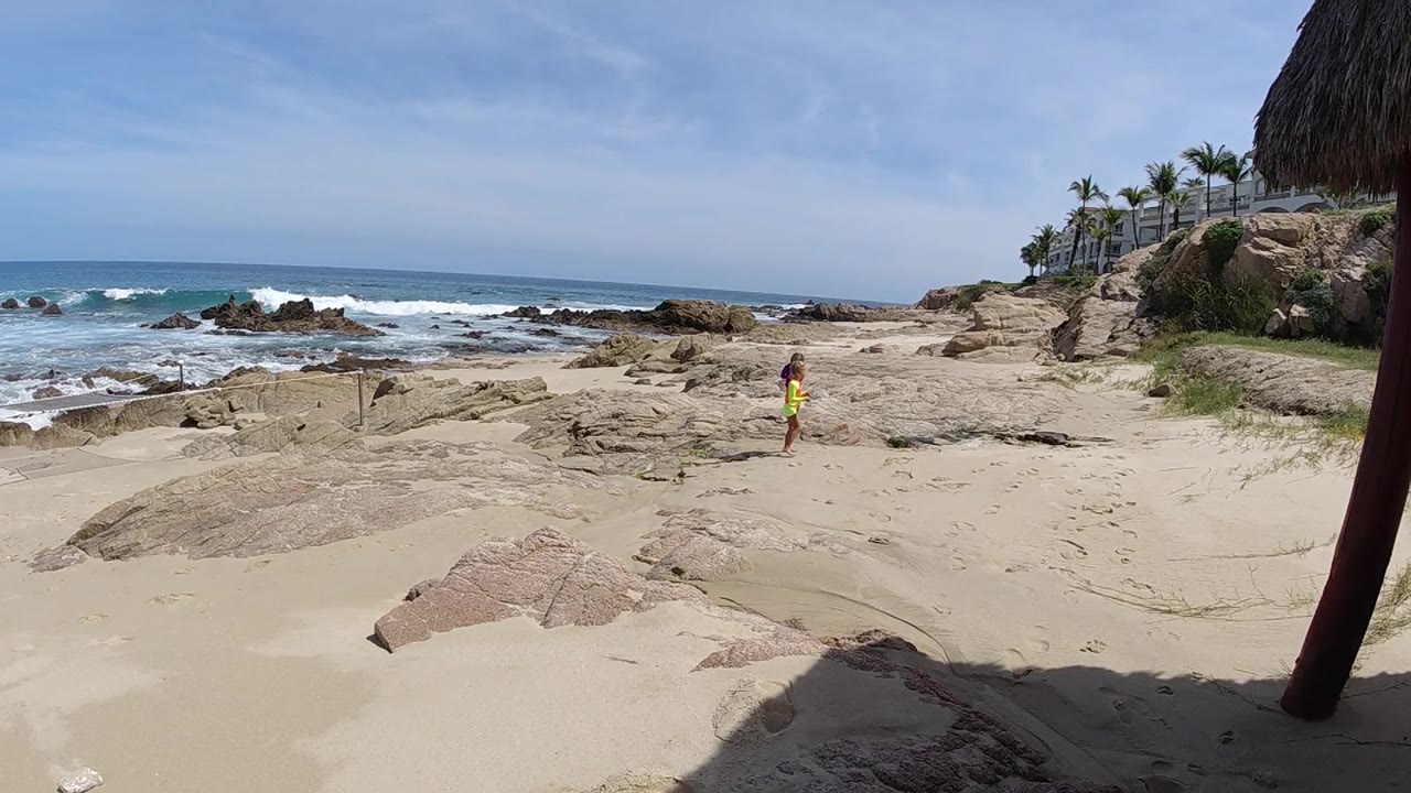 Sandy rock beach with waves and distant person