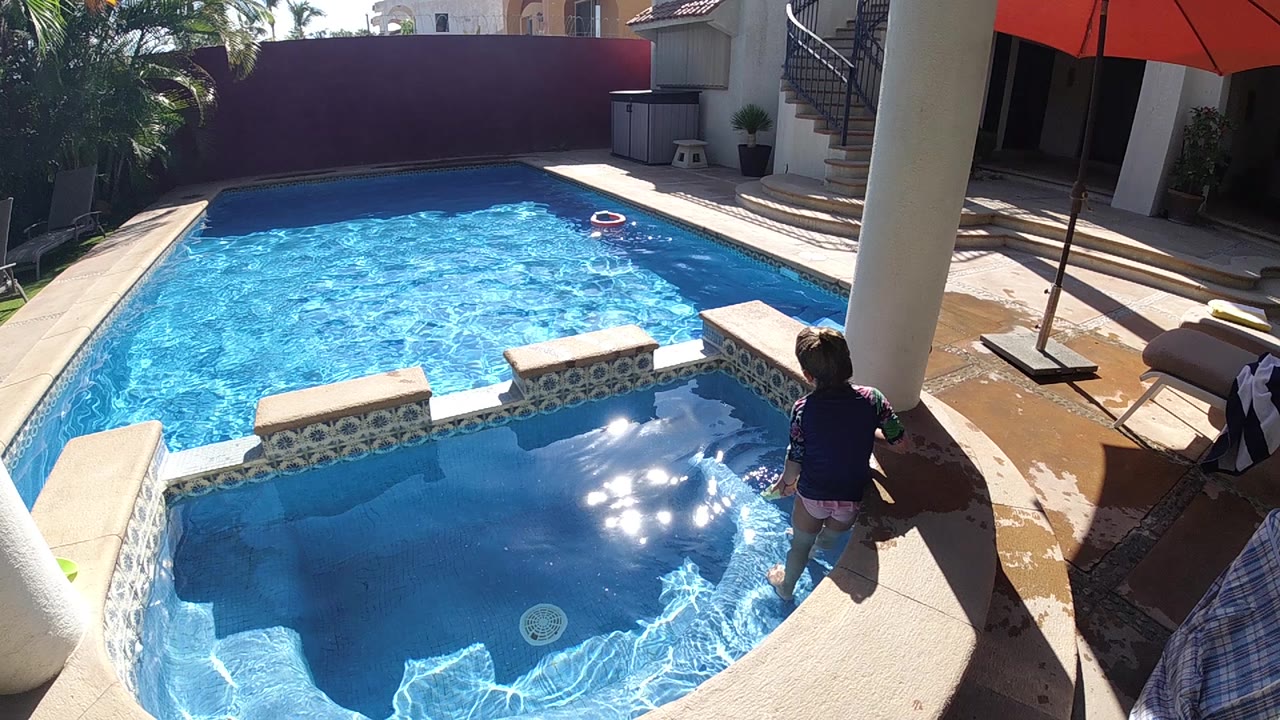 Child splashing near the spa edge with bright reflections on the pool water.