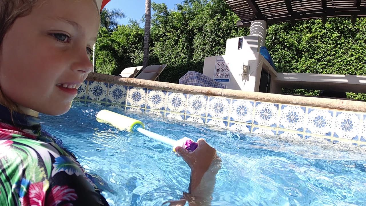 Side view of a young girl playing in pool water.