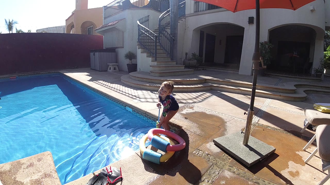 Child looks down near the inflatable ring at poolside.