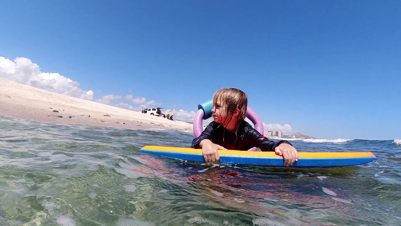 Girl lying on bodyboard near sandy beach