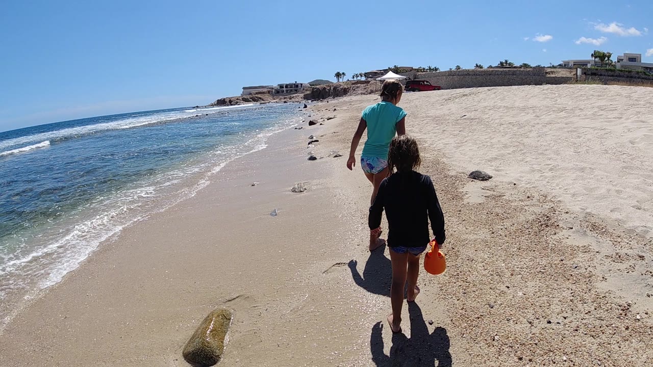 Man and child continue along the beach with waves rolling in at left.