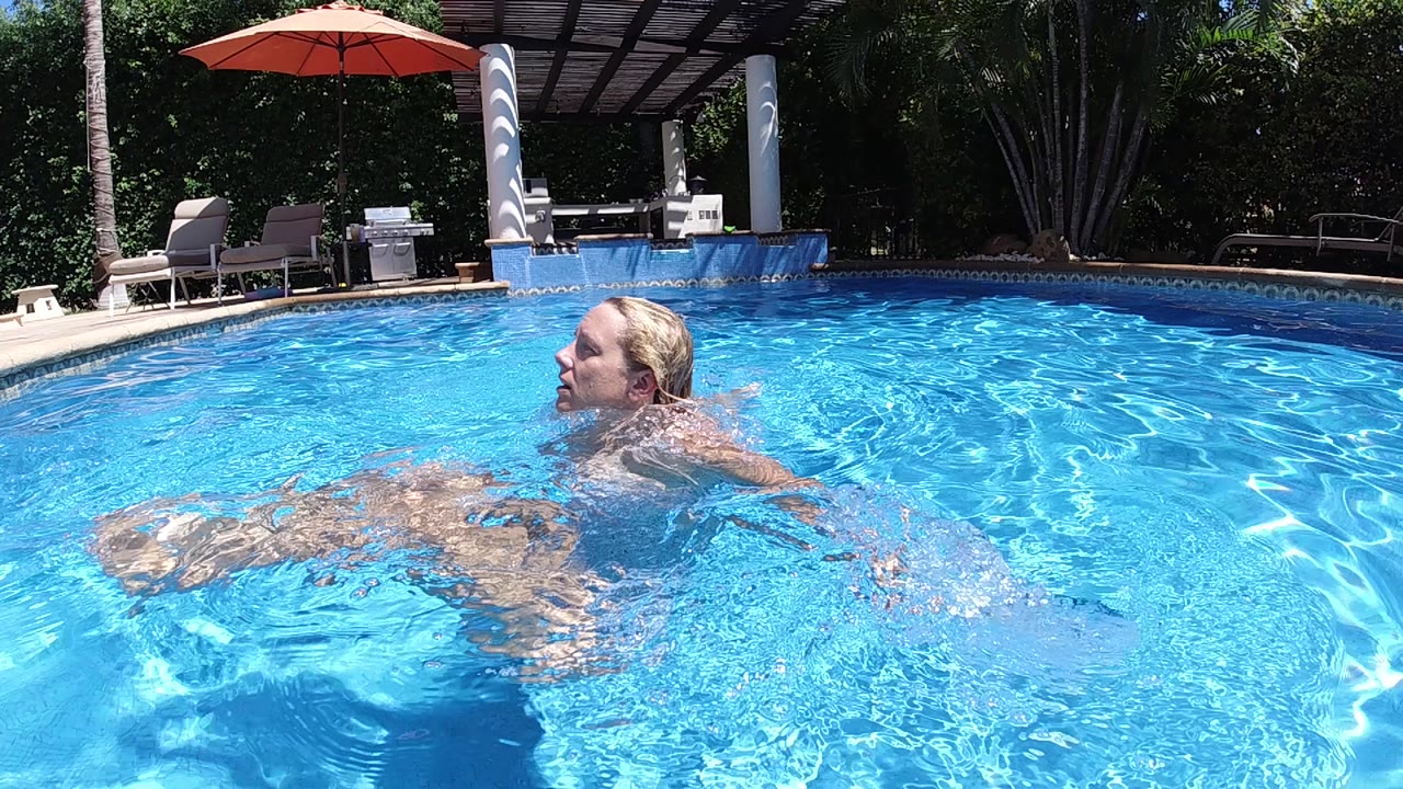 Woman gliding through blue pool water near the pool edge.