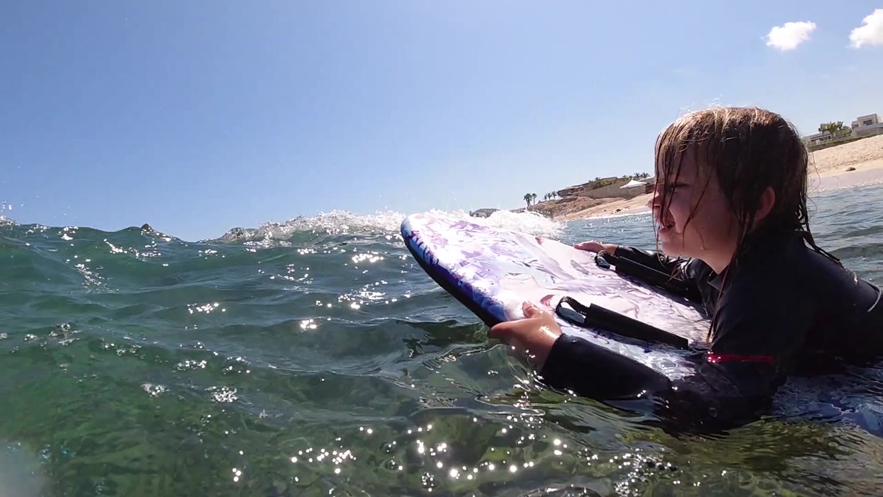 Surfer grips a surfboard as a wave lifts in front of the camera.