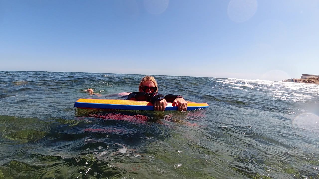 Surfer paddling on a striped board with low waves