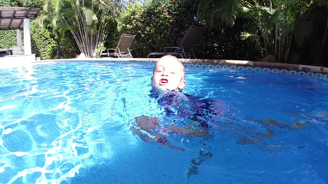 Young girl floats near the camera in bright blue water.