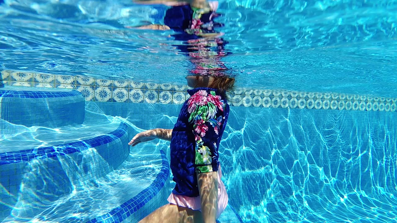 Underwater swimmer near tiled pool wall.