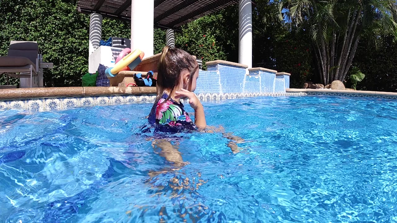 Girl standing in pool water with ripples around her legs.