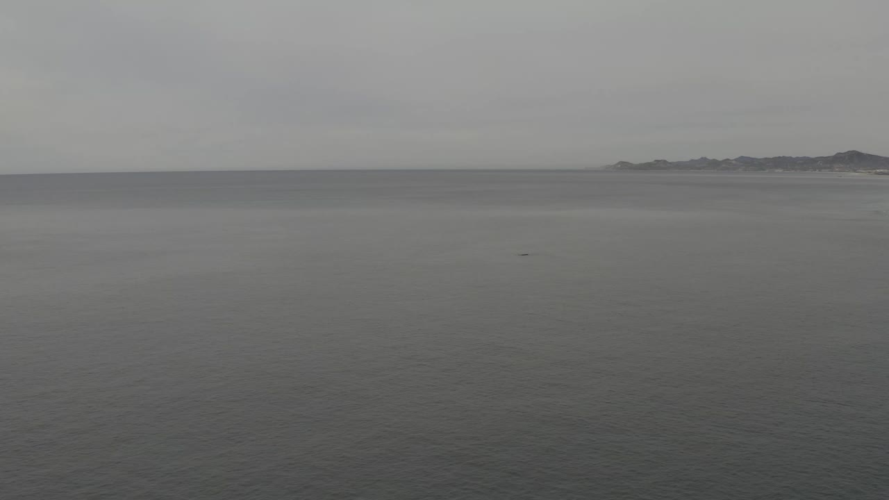 Wide grey sea with distant land on the horizon