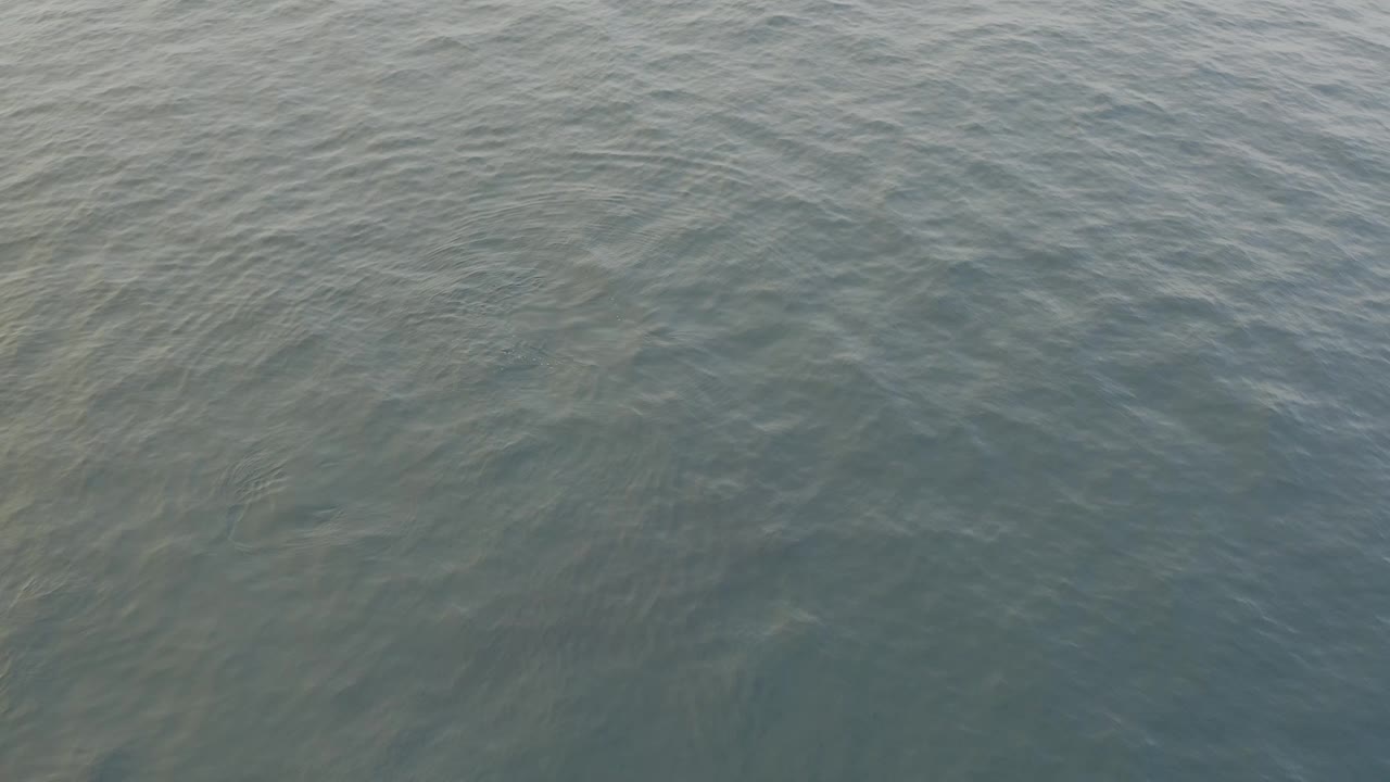 Grey-blue sea surface one second into the clip, showing faint diagonal ripple bands and a soft shift in water texture with no visible people.