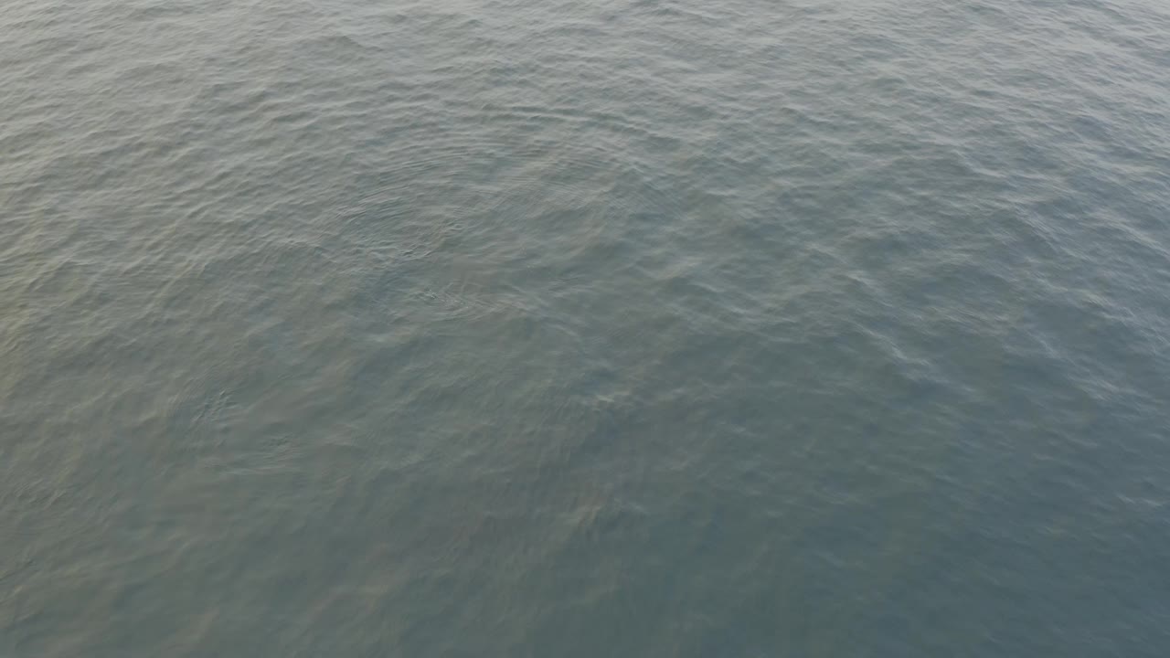 Overhead frame of grey ocean water filling the image, with fine ripples running across a flatter section of surface and no visible people.