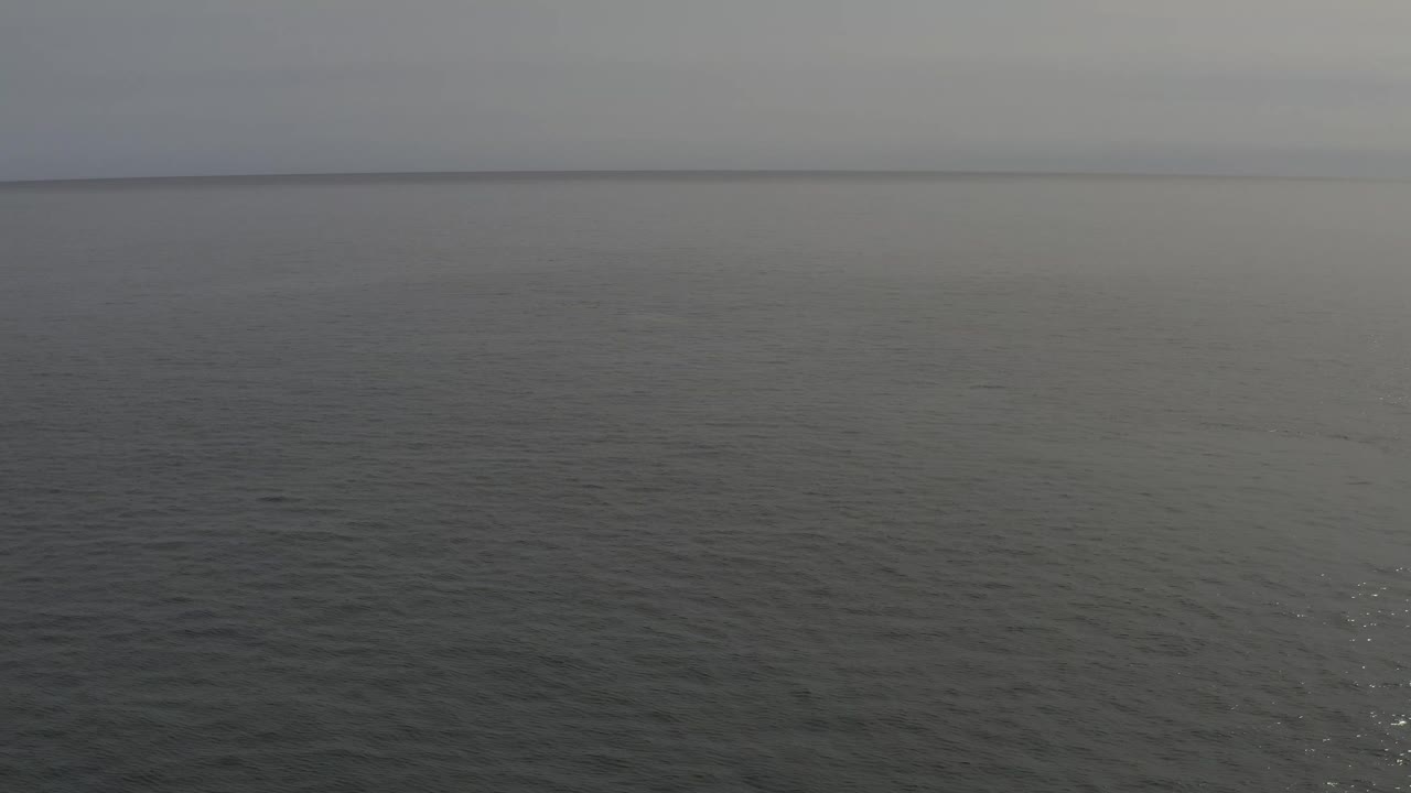 Grey ocean surface beneath a hazy horizon