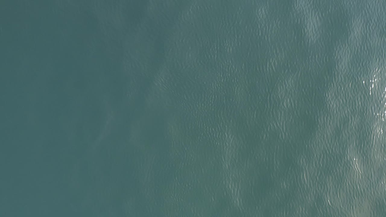 Top-down teal ocean surface with fine ripples.