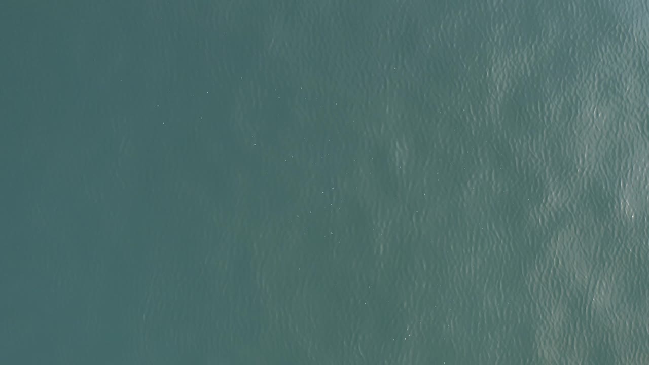 Top-down teal ocean surface with fine ripples.