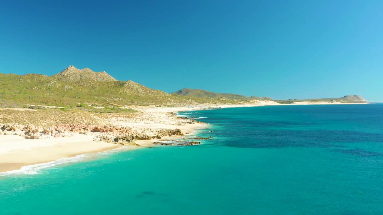 Aerial coastal view with shallow turquoise water and rocky shoreline.