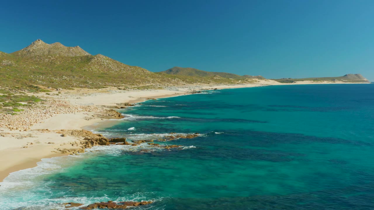 White waves breaking over rocks along a turquoise bay