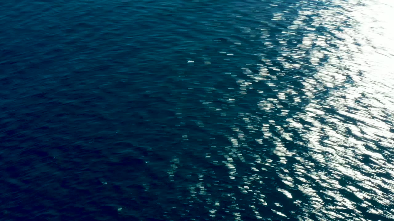Blue ocean surface at Buzzards Beach East Cape with a broad bright reflection crossing the upper right water, no visible people.