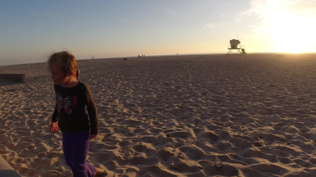 Young girl beside open sand and sunset horizon