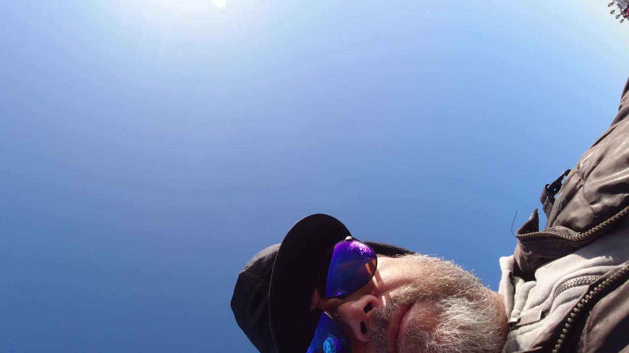 A partial close frame shows a man wearing a dark cap and reflective sunglasses at the edge of the image, with blue sky behind him in the Pismo Beach clip.