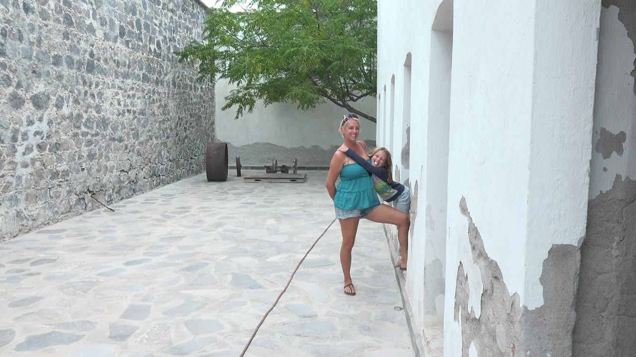 The woman and child are still visible near the right side of the Mulege BCS Mexico courtyard, with the white building beginning to obscure their path.