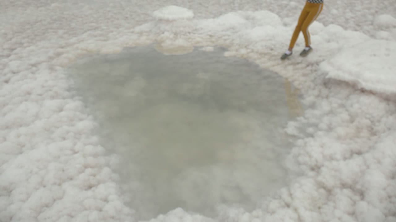At 0:02 in Guerrero Negro BCS Mexico, the child is cropped at the upper right while the frame centers on a pale pool bordered by rough white salt deposits.