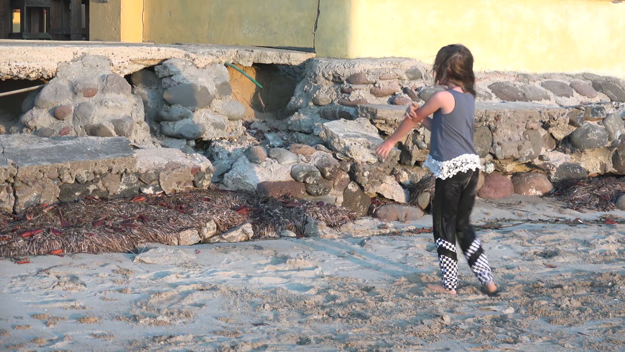 Girl turning near sand and stonework.