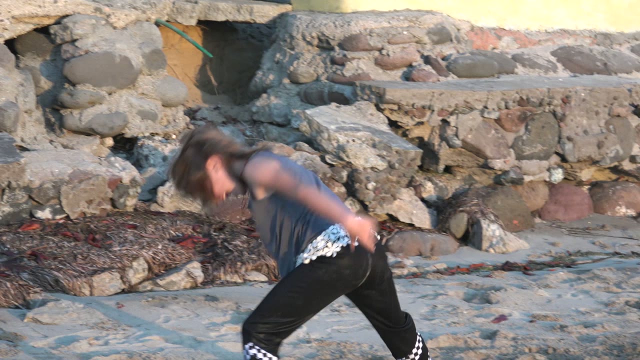 Child bending forward during a cartwheel on the beach.